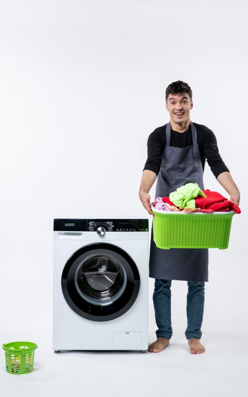 front-view-young-male-holding-basket-full-dirty-clothes-white-wall